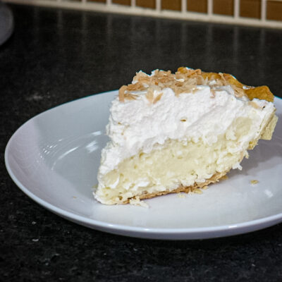 A slice of coconut cream pie with toasted coconut garnish