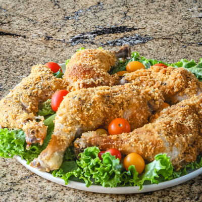 Cornflake crusted chicken on a platter with tomatoes and lettuce.
