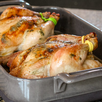 Garlic and cilantro butter cornish game hens in a roasting pan