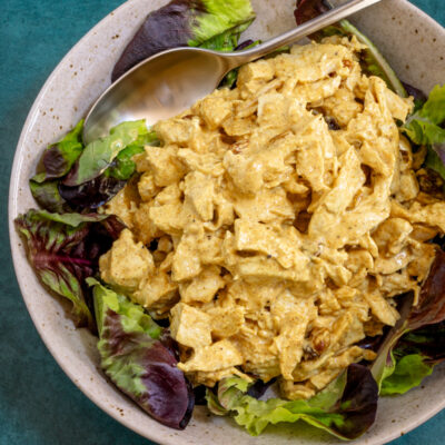 coronation chicken with curry powder in a lettuce-lined bowl
