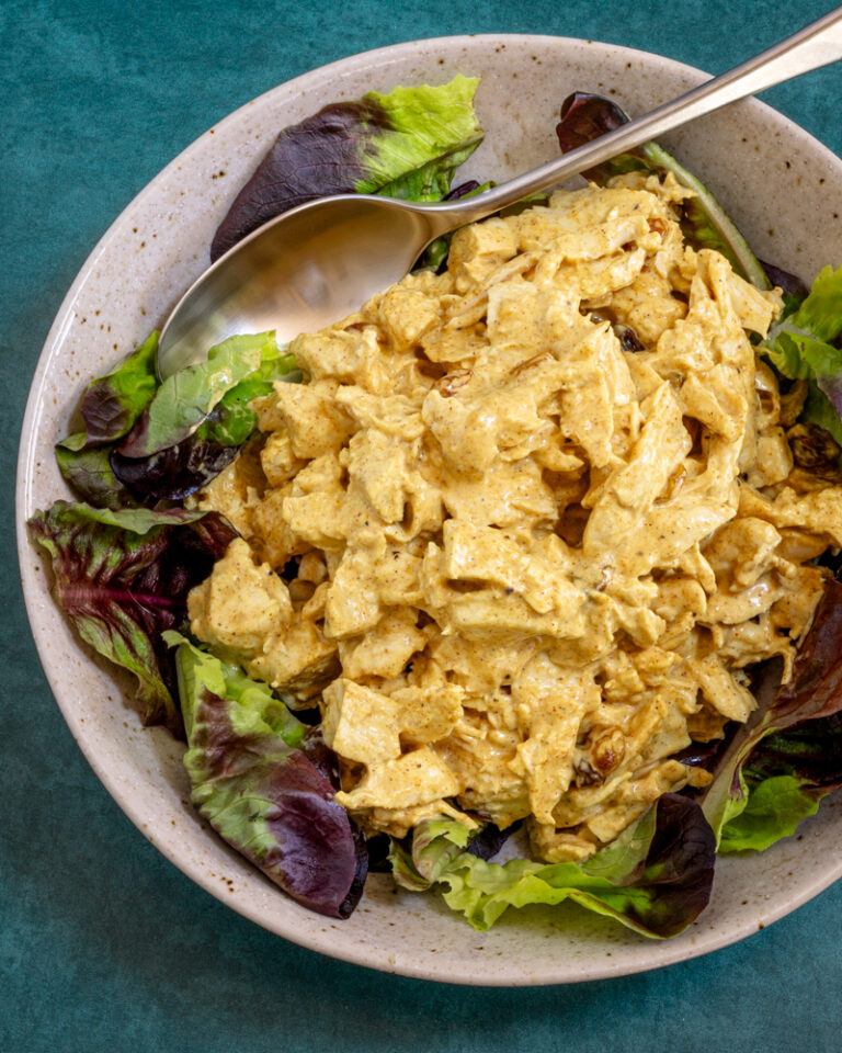 coronation chicken with curry powder in a lettuce-lined bowl