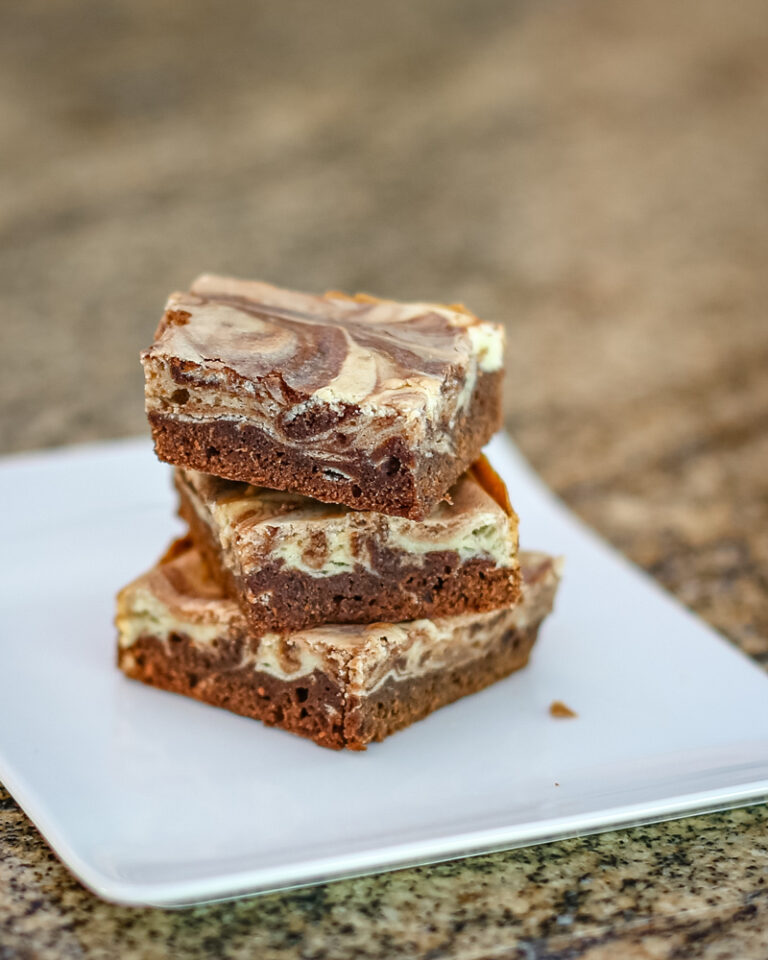 chocolate and cream cheese swirl brownies on a white plate