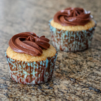 Cupcakes on the countertop, frosted with creamy chocolate frosting.