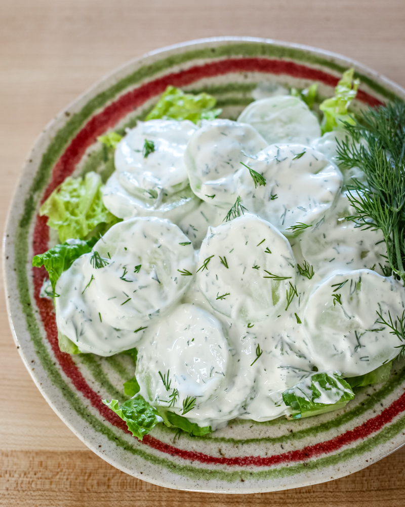 cucumber salad with sour cream and dill on a colorful plate