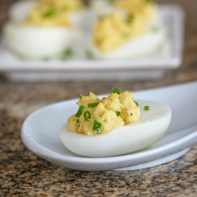 Curry deviled eggs on white appetizer plates.