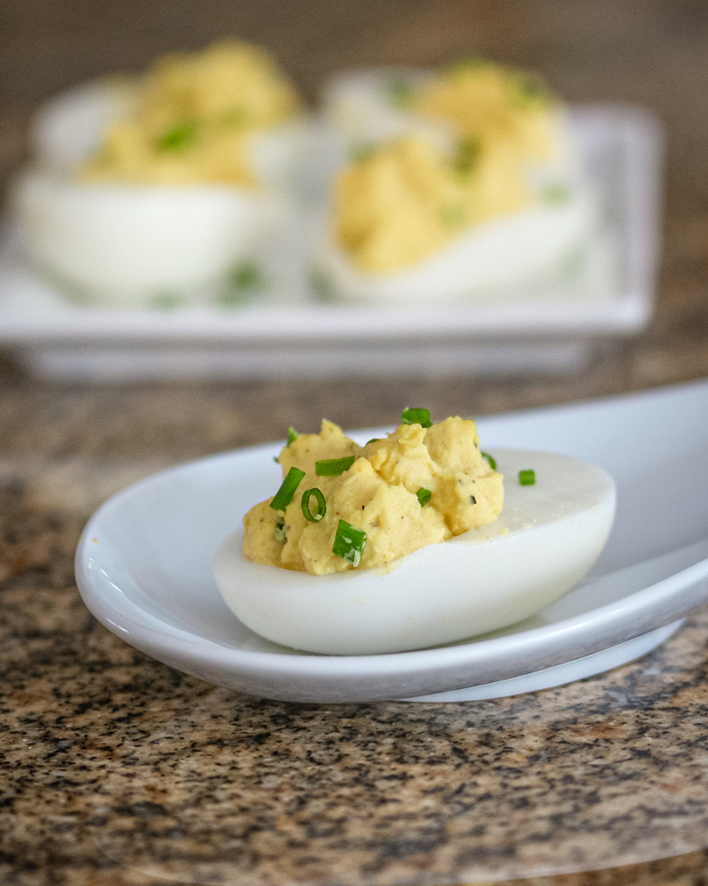 Curry deviled eggs on white appetizer plates.