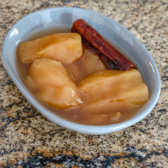 slow cooked apples in a small dish with a cinnamon stick