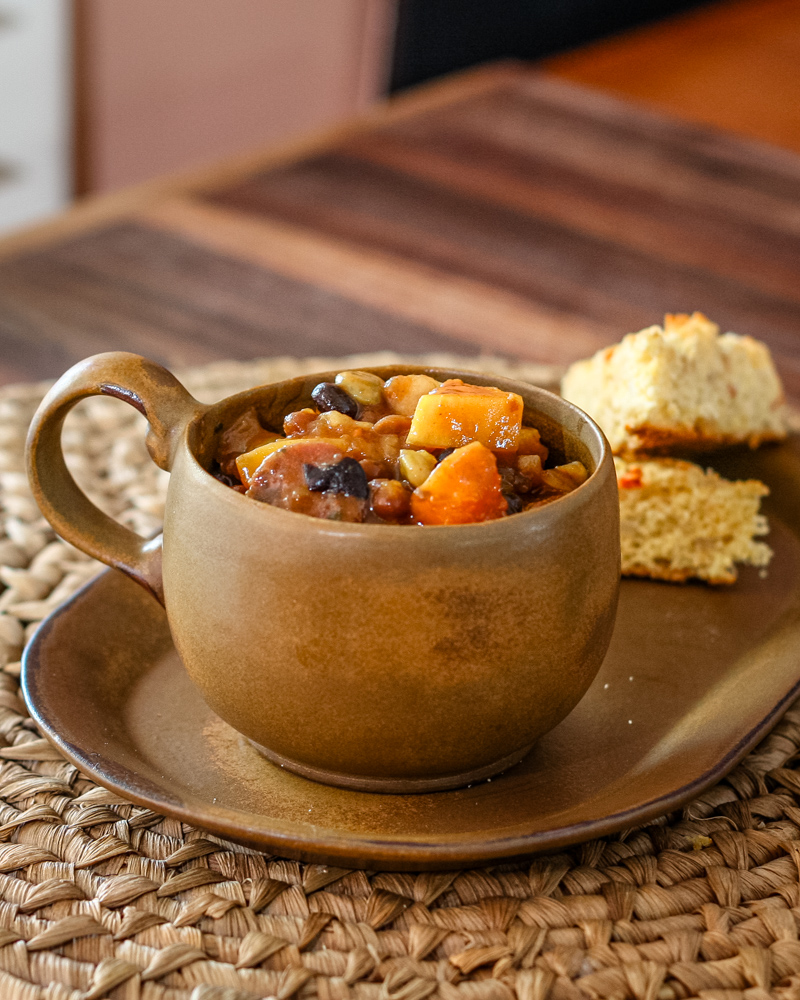baked beans with butternut squash and smoked sausage on a plate with cornbread
