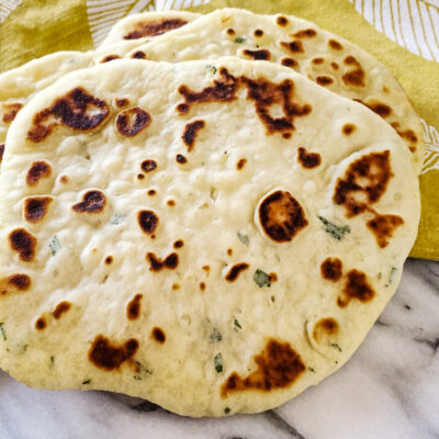 Homemade garlic naan on a yellow towel.