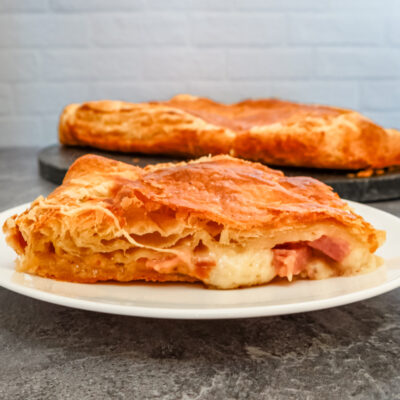 a slice of ham, gruyere, and fig tart on a white plate