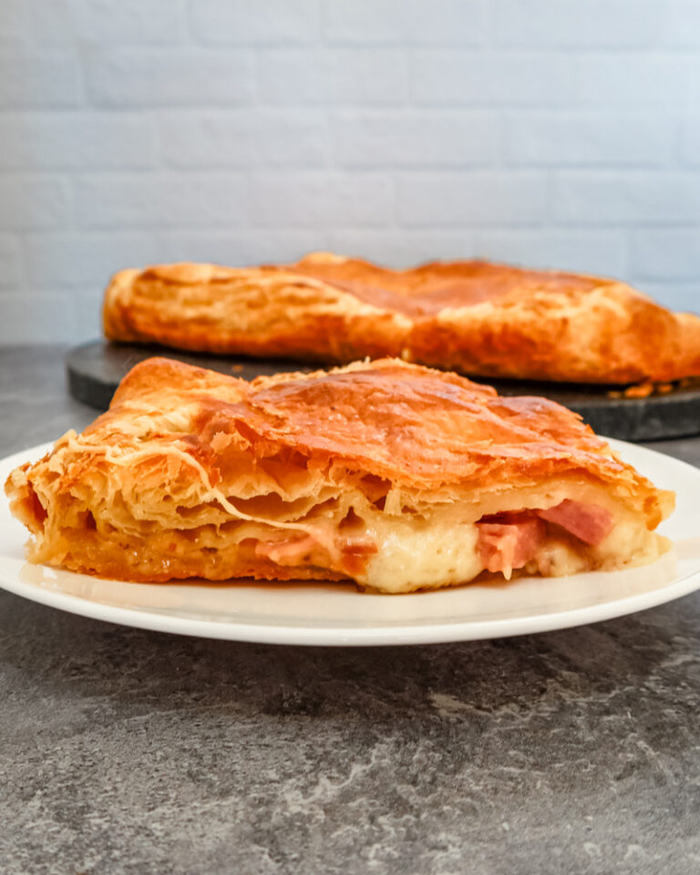 a slice of ham, gruyere, and fig tart on a white plate