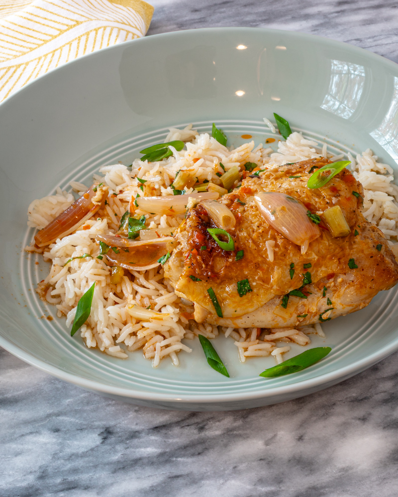 easy harissa chicken thighs shown with green onion garnish on rice