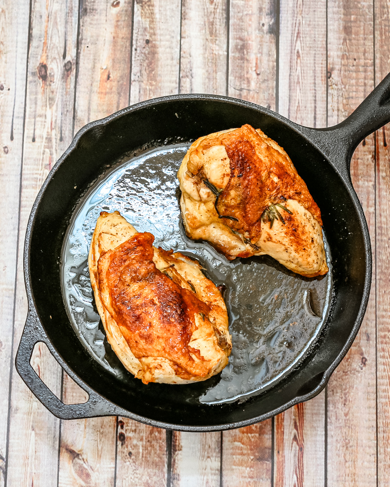 Herb roasted split chicken breasts in a cast iron pan