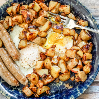 Golden roasted potatoes and fried eggs on a rustic plate.