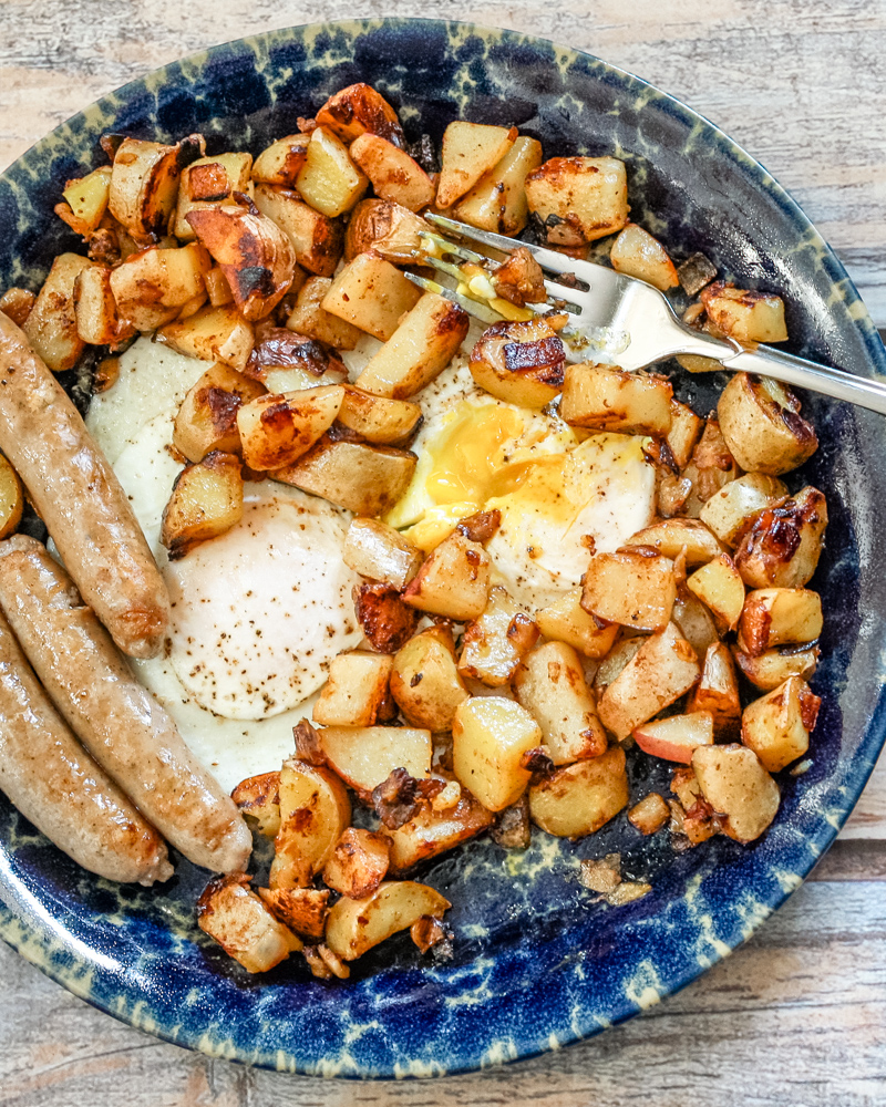 Golden roasted potatoes and fried eggs on a rustic plate.