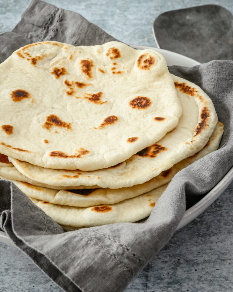 homemade naan bread on a kitchen towel.
