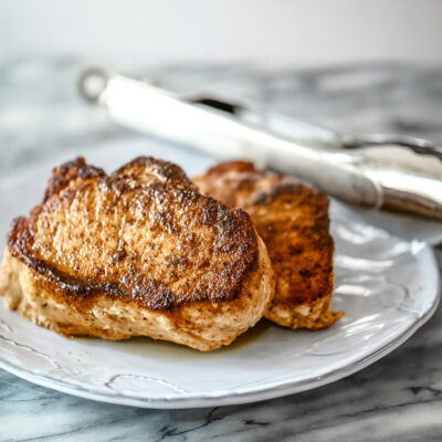 Instant Pot pressure cooker pork chops on a serving plate with tongs in the background.