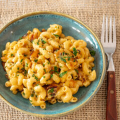Creamy bacon macaroni and cheese with chopped herbs on top.