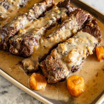 Instant Pot beef short ribs on a serving tray with carrots and sauce.