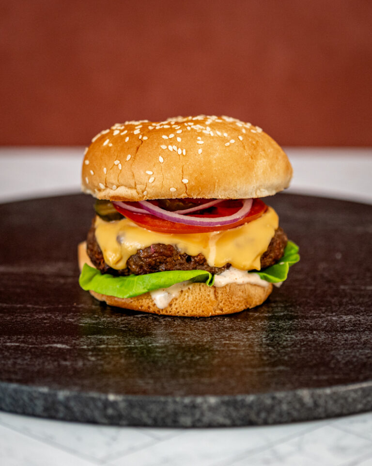Instant Pot burger in a sesame seed bun with cheese and toppings.