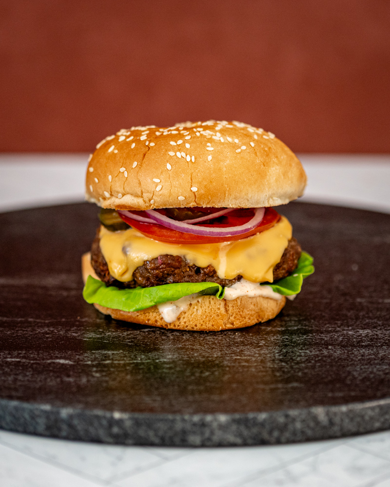 Instant Pot burger in a sesame seed bun with cheese and toppings.