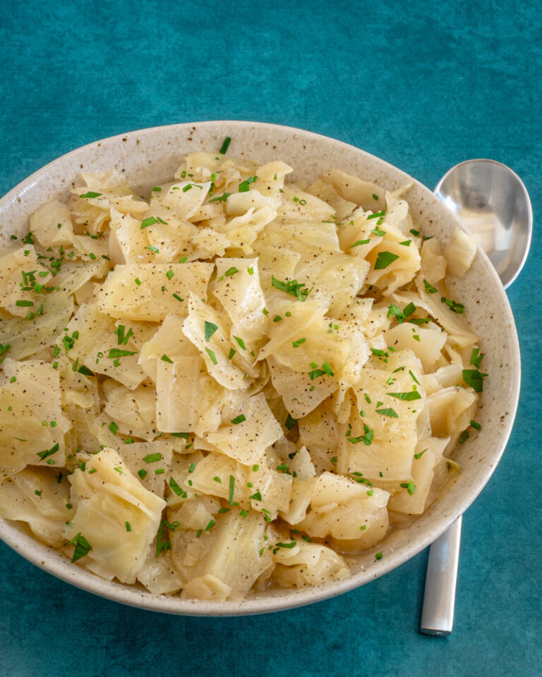 A serving bowl with Instant Pot cooked cabbage, garnished with parsley.