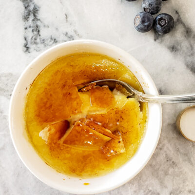 Creme brulee in a small white ramekin with blueberries.