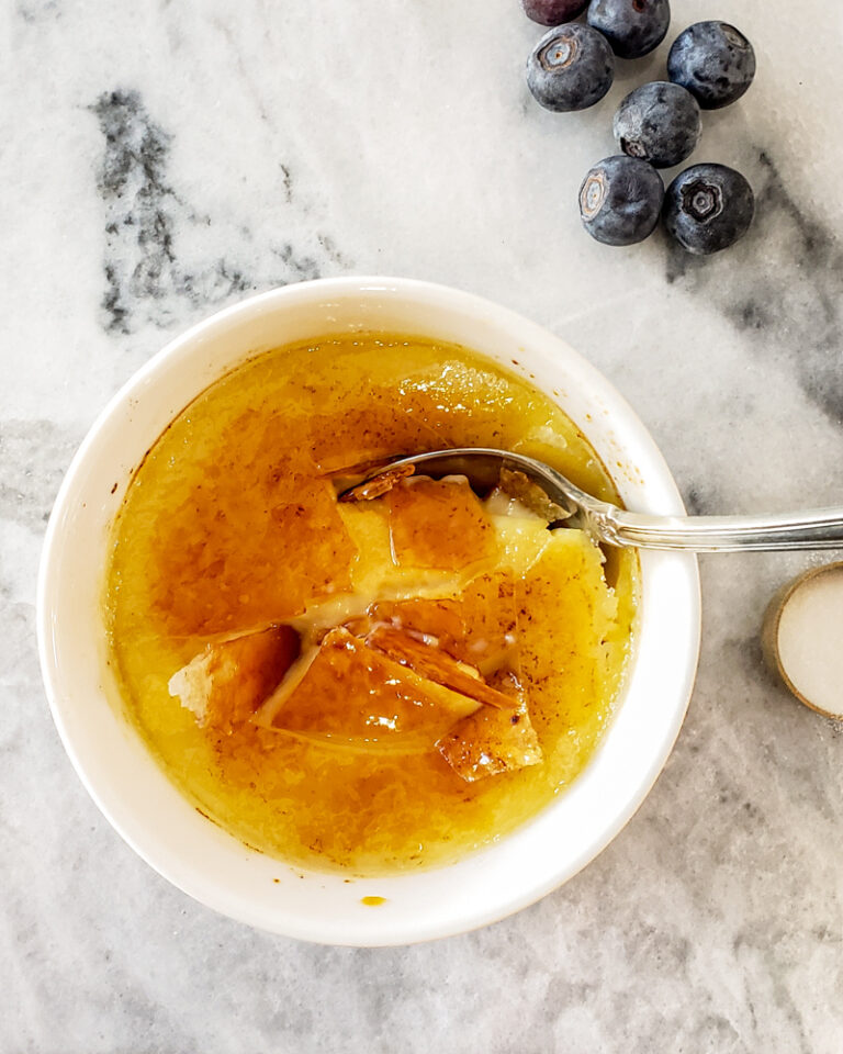 Creme brulee in a small white ramekin with blueberries.