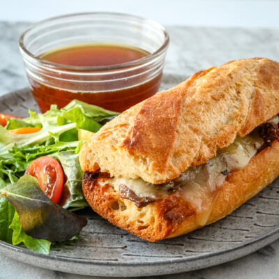 An Instant Pot French dip sandwich with cheese in a toasted crusty roll.
