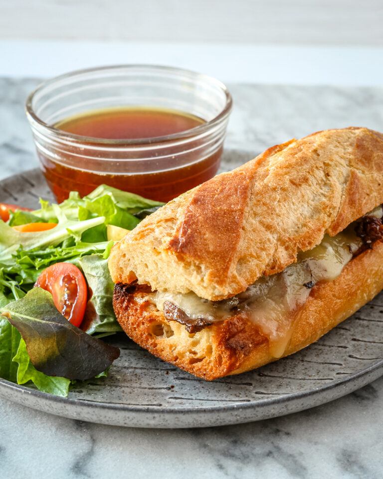 An Instant Pot French dip sandwich with cheese in a toasted crusty roll.
