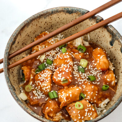 General Tso's chicken in a bowl with chopsticks.