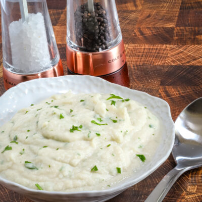 Creamy mashed cauliflower garnished with chopped herbs.
