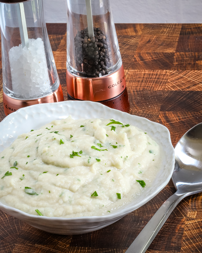 Creamy mashed cauliflower garnished with chopped herbs.