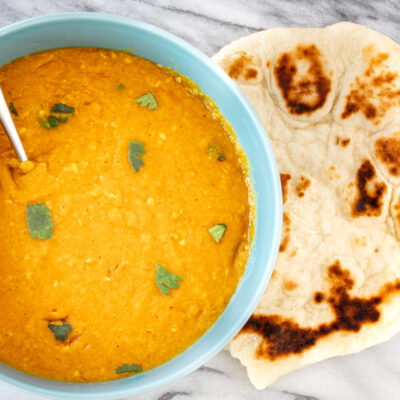 Creamy lentil dal garnished with fresh cilantro, served with toasted naan bread.