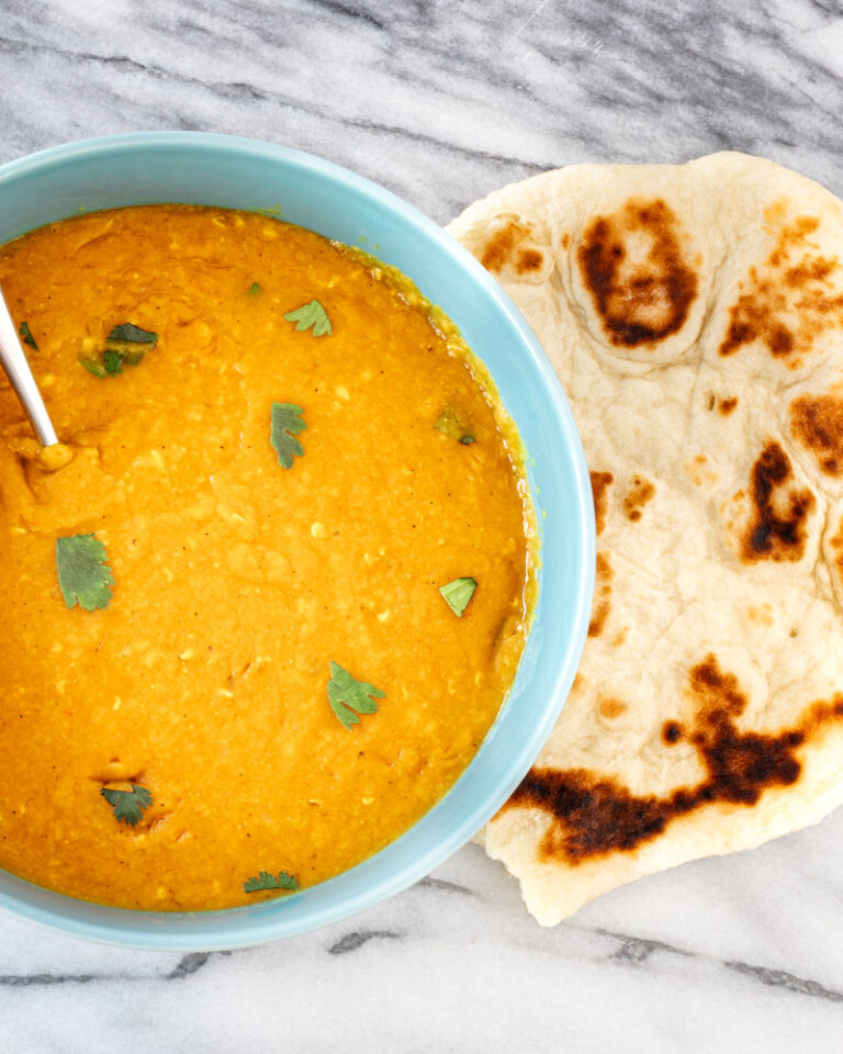 Creamy lentil dal garnished with fresh cilantro, served with toasted naan bread.