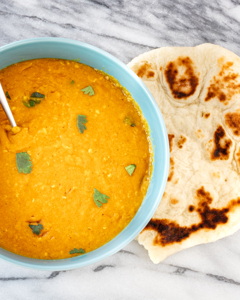 Creamy lentil dal garnished with fresh cilantro, served with toasted naan bread.