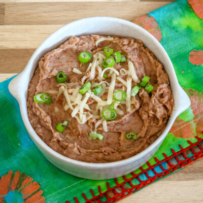 Refried beans from the Instant Pot, garnished with cheese and green onions.