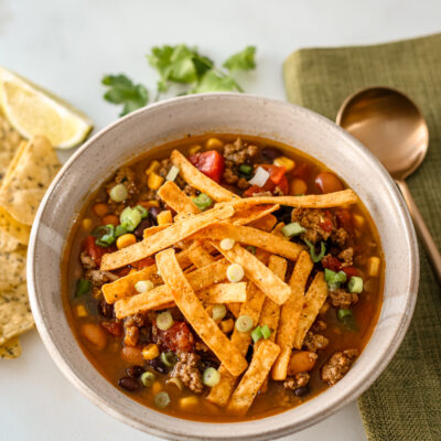 A bowl of taco soup with chips on the side.