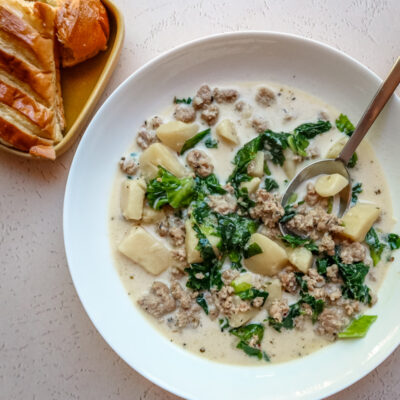 Instant pot zuppa Toscana soup in a white bowl with bread on the side.