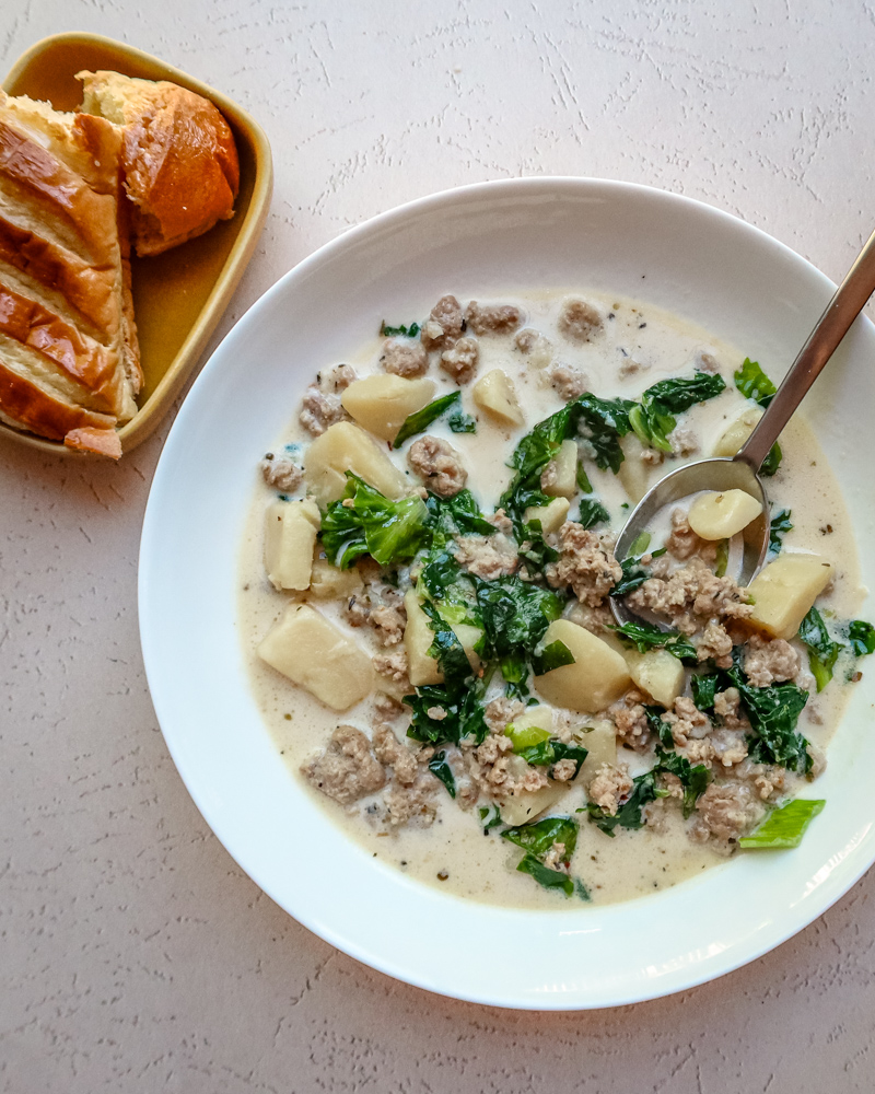 Instant pot zuppa Toscana soup in a white bowl with bread on the side.