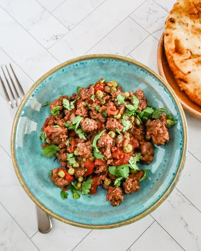 A serving of keema matar with naan bread on the side.