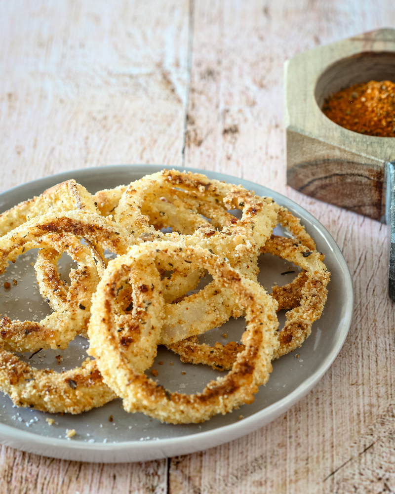 keto onion rings on a plate with salt and pepper on the side.