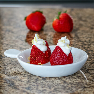 Lemon and cream cheese filled strawberries in a small appetizer dish.