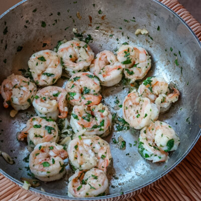 Shrimp scampi in a skillet with parsley garnish.