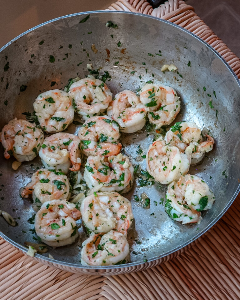Shrimp scampi in a skillet with parsley garnish.