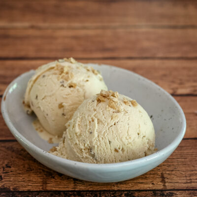 maple walnut ice cream in a bowl with maple flakes garnish