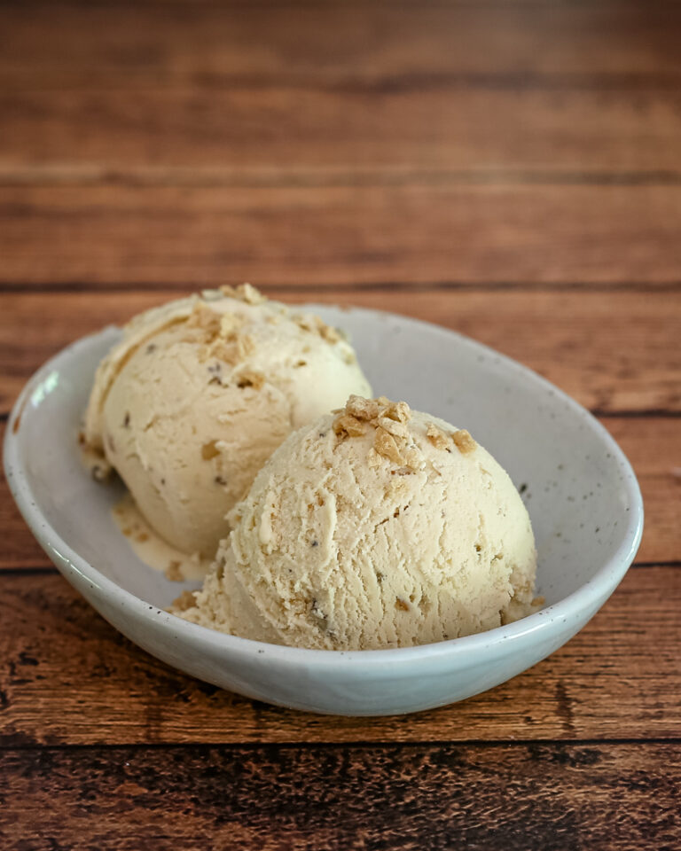 maple walnut ice cream in a bowl with maple flakes garnish