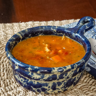 Warm bowl of mulligatawny soup in a decorative blue and white ceramic dish.