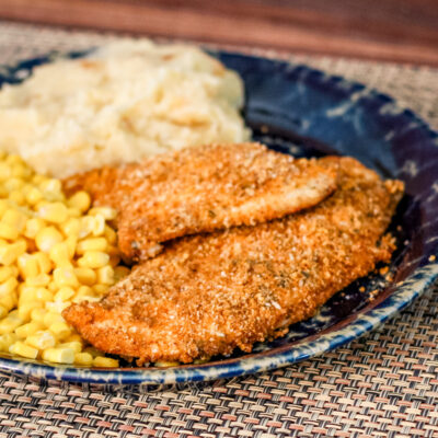 Panko crusted oven fried chicken on a plate with mashed potatoes and corn.