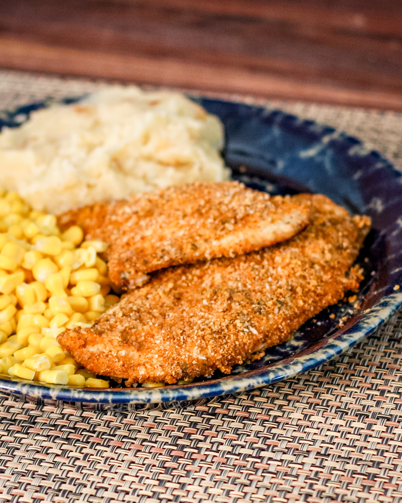 Panko crusted oven fried chicken on a plate with mashed potatoes and corn.